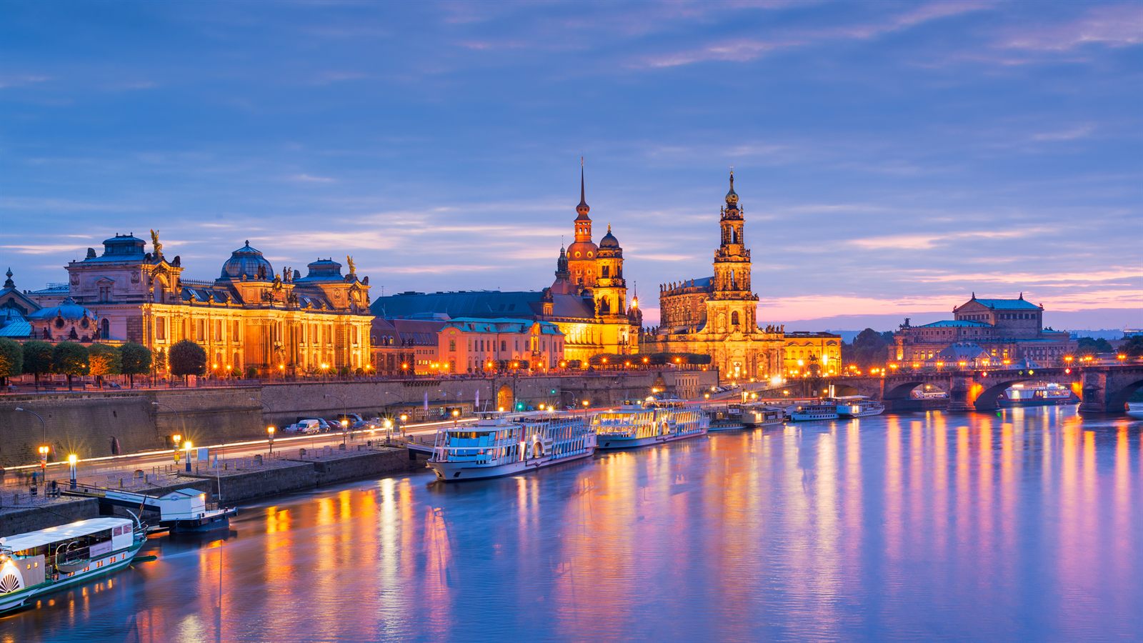 Dresden skyline with domes and spires lit up above the Elbe at night, a highlight of Elbe river cruises